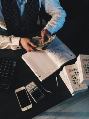Businessman organizing finances with tech devices and cash on desk.
